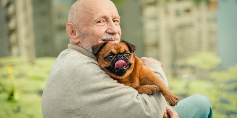 Elderly Man Holding Small Dog at Assisted Living Facility