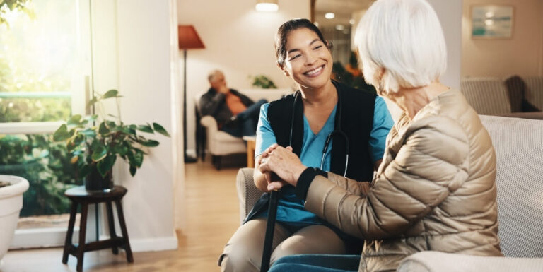 Female Nurse Holding Hands with Resident at Assisted Living Facility